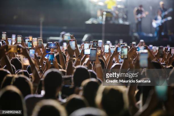 Concertgoers record videos and take photos with their smartphones as Jonas Brothers perform live on stage during a concert on April 16, 2024 in Sao...