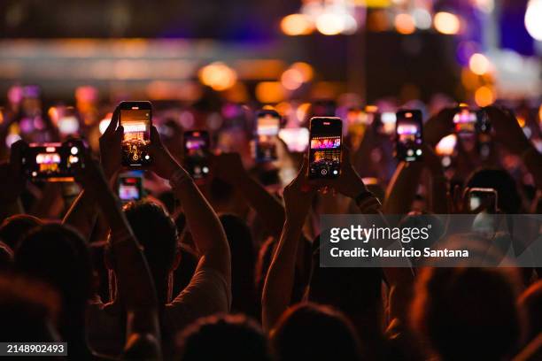 Concertgoers record videos and take photos with their smartphones as Jonas Brothers performs live on stage during a concert on April 16, 2024 in Sao...