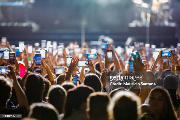 Concertgoers record videos and take photos with their smartphones as Jonas Brothers performs live on stage during a concert on April 16, 2024 in Sao...