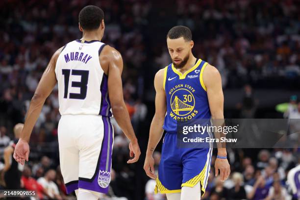 Stephen Curry of the Golden State Warriors walks back downcourt with his head down next to Keegan Murray of the Sacramento Kings in the first quarter...