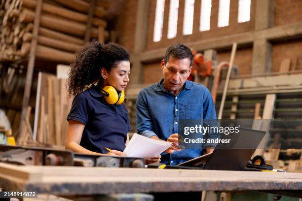 foreman giving instructions to a female worker at a wood factory - praktikant bildbanksfoton och bilder