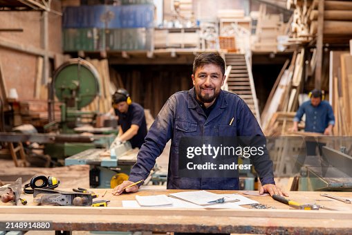 Man working at a wood factory and looking at the camera smiling Man working at a wood factory and looking at the camera smiling
