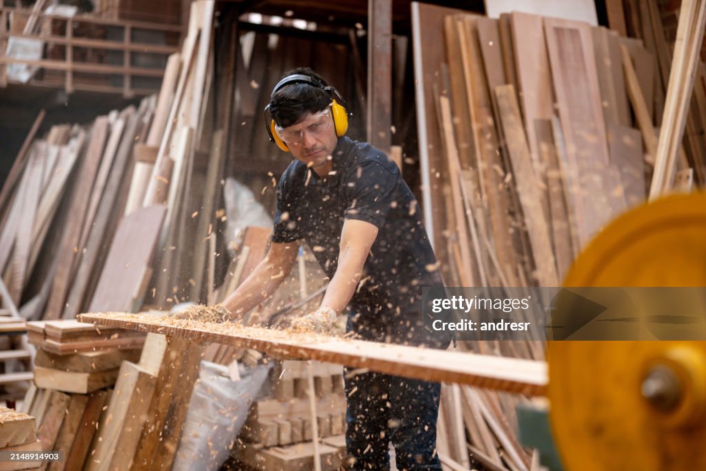 Trabajador lijando un tablón de madera en una fábrica de madera