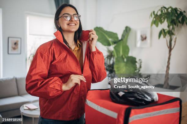female delivery person preparing for assignments - person putting on jacket stock pictures, royalty-free photos & images