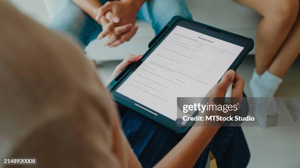 asian sadness couple doing a mental health survey on a tablet with a female psychotherapist. professional social worker assist married couples with empathy. - vragenlijst stockfoto's en -beelden