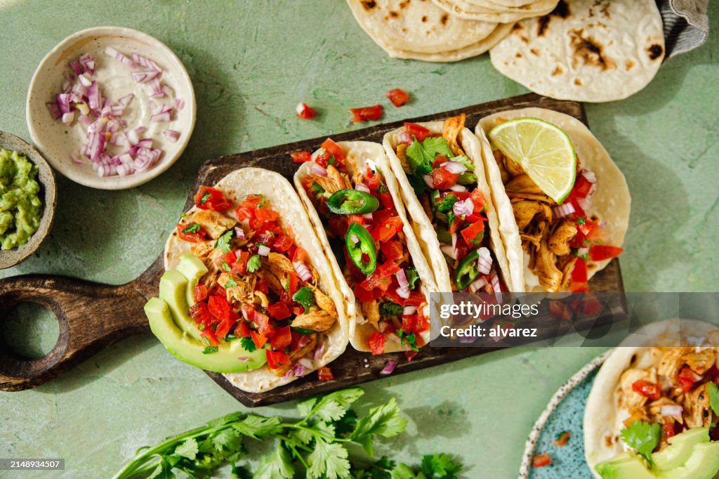 Homemade tacos served on table with ingredients around