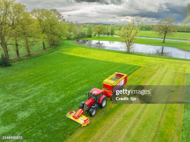 tractor mowing and collecting grass in a meadow during springtime - silage cutter stock pictures, royalty-free photos & images