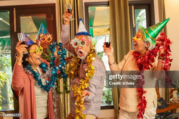 joyful senior friends in props dancing with wineglasses while partying together at home during weekend - party funny stock pictures, royalty-free photos & images