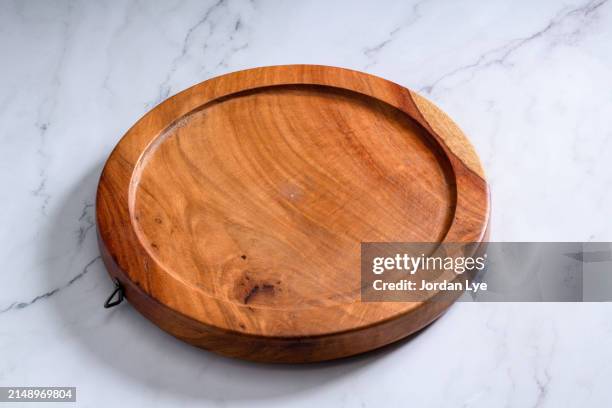 round wooden cutting board on a marble table - tabla de cortar fotografías e imágenes de stock