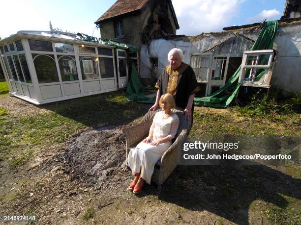 English film director and photographer Ken Russell posed with his wife, American actress Elize Tribble, outside their fire damaged cottage in the...