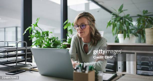 computadora portátil, brazos cruzados y mujer de negocios madura en el escritorio en la oficina de vidrio para la administración o el informe en línea. computadora, correo electrónico e investigación con empleado seguro en la mesa en el lugar de traba - usar el ordenador fotografías e imágenes de stock