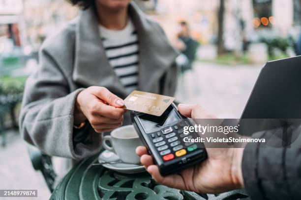young woman paying contactless with credit card in a sidewalk cafe. - dichterbij komen stockfoto's en -beelden
