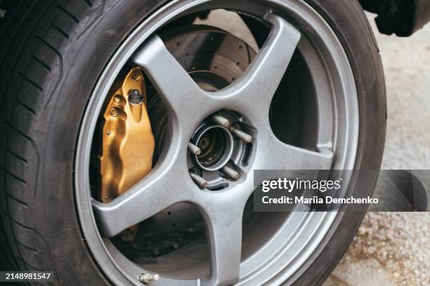 car wheel with golden brake caliper - bloque de freno fotografías e imágenes de stock