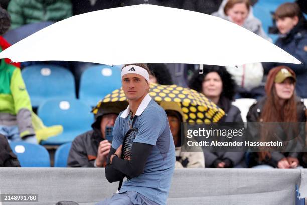 Alexander Zverev of Germany sit under a umbrella during a rain break at his second round match against Jurij Rodionov of Austria on day 5 of the BMW...