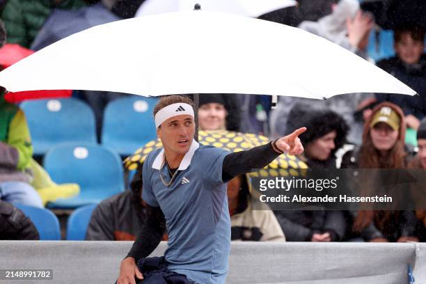 Alexander Zverev of Germany reacts as hi sit under a umbrella during a rain break at his second round match against Jurij Rodionov of Austria on day...