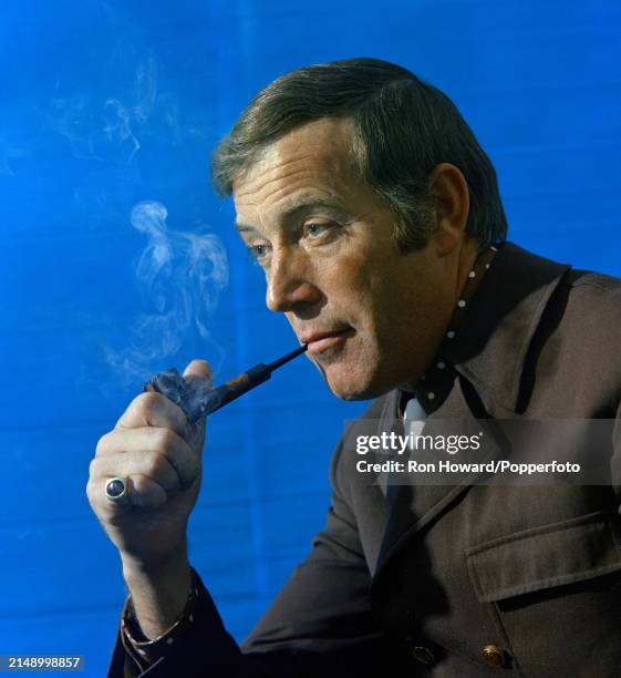 Irish singer Val Doonican posed smoking a pipe, in England circa 1970.