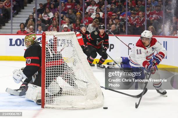 Brendan Gallagher of the Montreal Canadiens makes a diving play to pass the puck in front of Joonas Korpisalo of the Ottawa Senators net during the...
