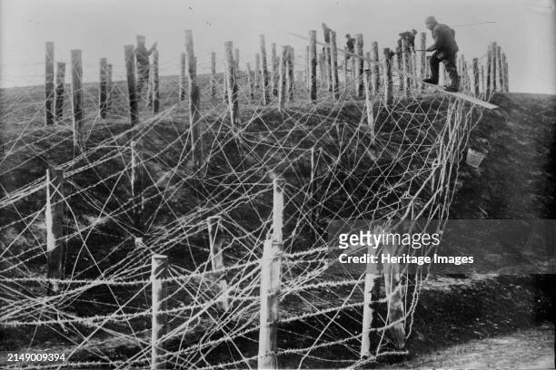 Germans fixing barbed wire tangle, between circa 1914 and circa 1915. German soldiers fixing a barbed wire entanglement during World War I. Creator:...