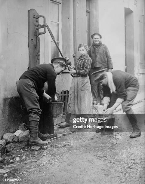 Tommy Atkins at Etaples, between 1914 and circa 1915. Two British soldiers called 'Tommys,' helping some local residents at a water pump, E´taples,...