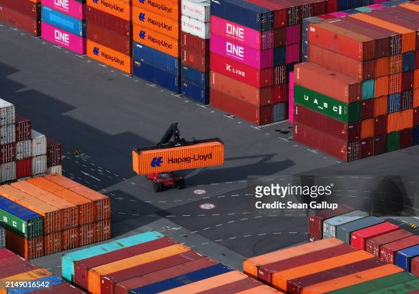 In this aerial view a freight-carrying vehicle called a straddle carrier, or straddle truck, transports a Hapag-Lloyd shipping container among...