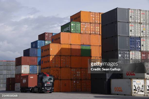 Truck stands next to shipping containers stacked at Hamburg Port on April 17, 2024 in Hamburg, Germany. The International Monetary Fund has reduced...