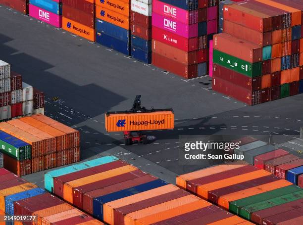 In this aerial view a freight-carrying vehicle called a straddle carrier, or straddle truck, transports a Hapag-Lloyd shipping container among...