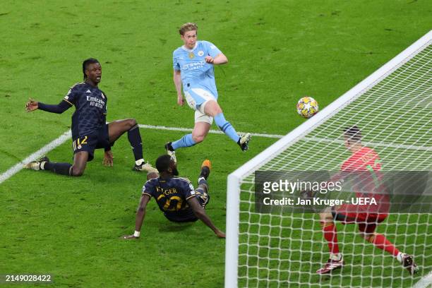 Kevin De Bruyne of Manchester City scores his team's first goal past Andriy Lunin of Real Madrid whilst under pressure from Eduardo Camavinga and...