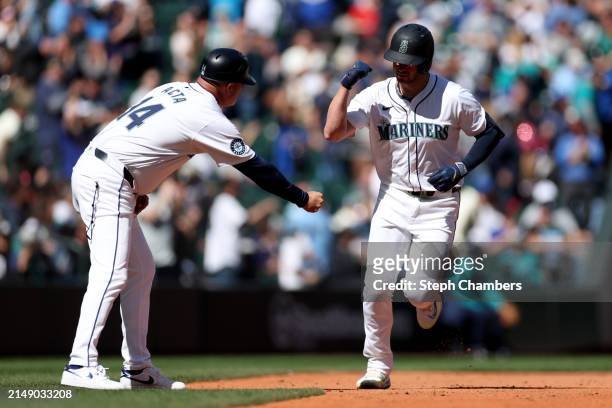Mitch Garver of the Seattle Mariners celebrates his home run with third base coach Manny Acta during the sixth inning against the Cincinnati Reds at...
