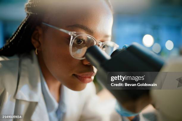 scientist, black woman and microscope for research, laboratory or medical doctor in healthcare. microbiology, future or life extension drug experiment, futuristic or learning with chemistry in clinic - black scientist stock pictures, royalty-free photos & images