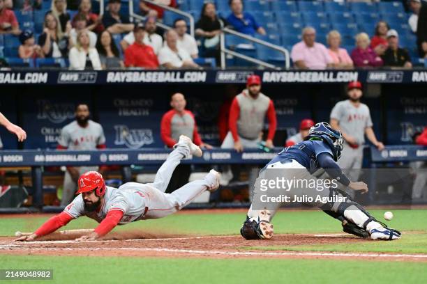 Anthony Rendon of the Los Angeles Angels slides into home plate past René Pinto of the Tampa Bay Rays to score the go-ahead run in the ninth inning...