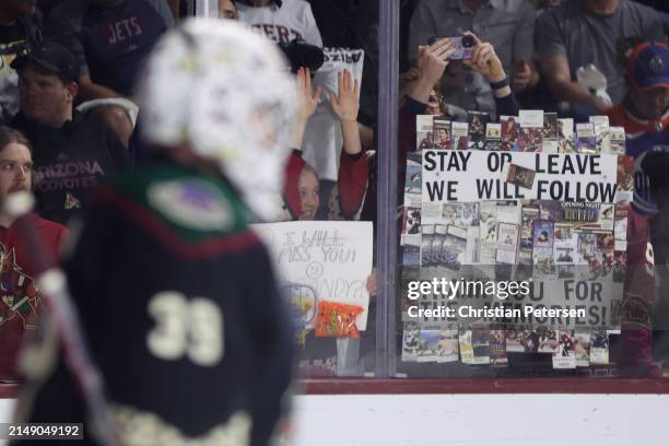 Fans hold up signs before the NHL game between the Edmonton Oilers and the Arizona Coyotes at Mullett Arena on April 17, 2024 in Tempe, Arizona....