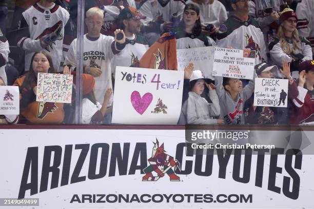 Fans hold up signs before the NHL game between the Edmonton Oilers and the Arizona Coyotes at Mullett Arena on April 17, 2024 in Tempe, Arizona....