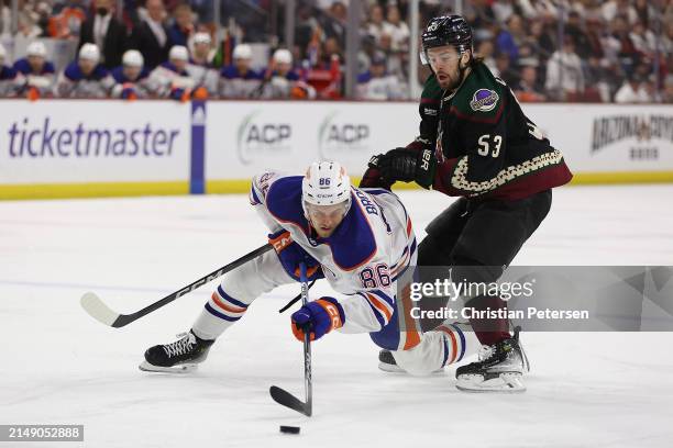 Philip Broberg of the Edmonton Oilers attempts to control the puck against Michael Carcone of the Arizona Coyotes during the first period of the NHL...