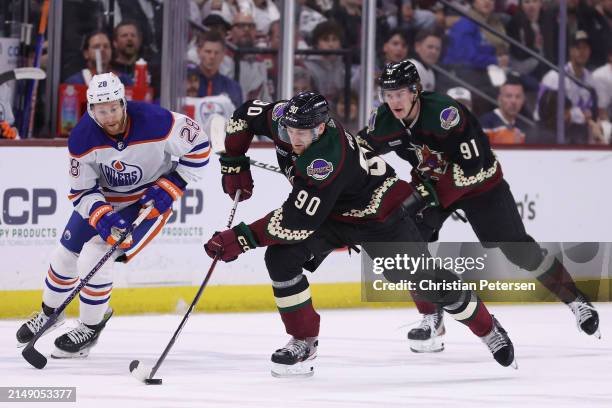 Moser of the Arizona Coyotes skates with the puck ahead of Connor Brown of the Edmonton Oilers and Josh Doan during the first period of the NHL game...