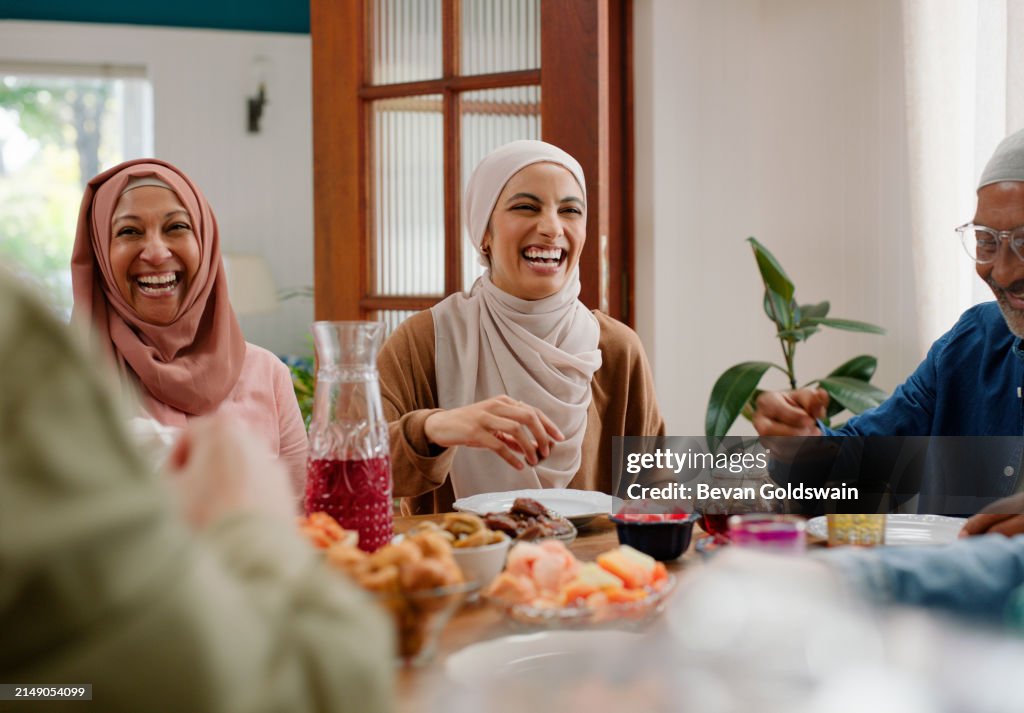 Famiglia, sorriso e cena per la celebrazione del Ramadan, persone musulmane nella sala da pranzo che mangiano, ridono e parlano. Islam, uomini e donne con cultura, cibo e felice festa di eid al fitr in casa.