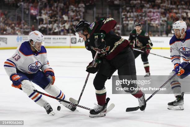 Josh Doan of the Arizona Coyotes skates with the puck against Mattias Janmark of the Edmonton Oilers during the second period of the NHL game at...