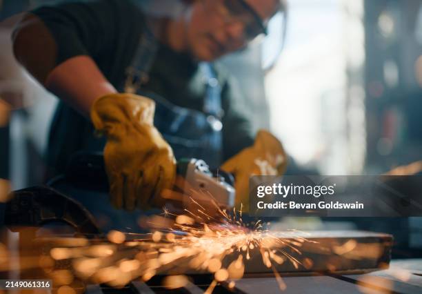 woman, angle grinder and sparks in workshop for metal production, manufacturing or steel. female person, tools and factory warehouse with construction equipment for diy repair, craft or contractor - elektrisch gereedschap stockfoto's en -beelden