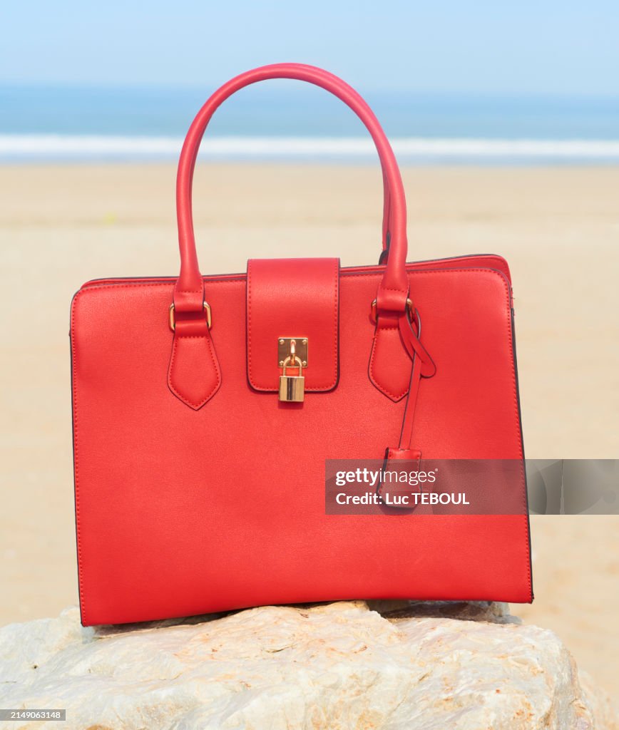 Red leather handbag on sea background