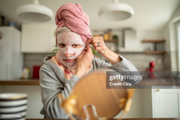 senior woman taking care of her face - body care and beauty stock pictures, royalty-free photos & images