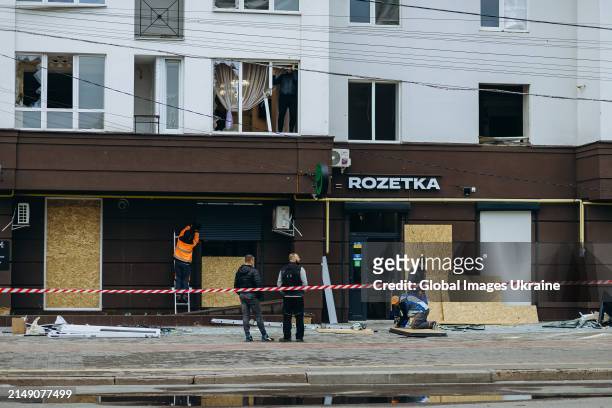 Utility workers install plywood boards instead broken windows in residential building damaged as result of Russian missile attack on April 17, 2024...