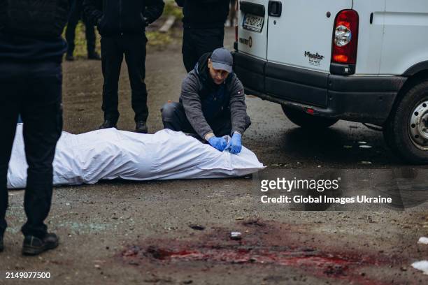 Rescuers put dead body in white body bag on the street after Russian missile attack on April 17, 2024 in Chernihiv, Ukraine. Russian forces launched...