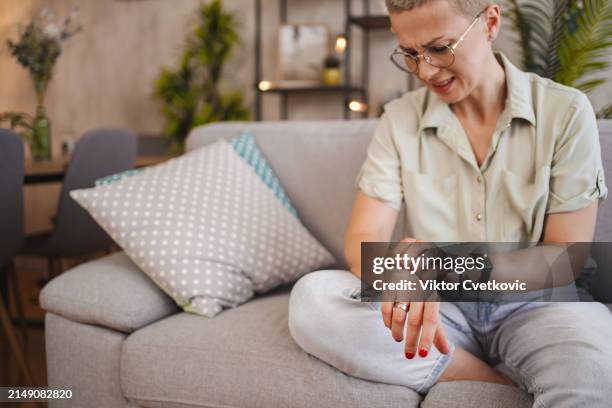 woman scratching her itchy forearm while at home - arranhar imagens e fotografias de stock