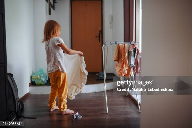 domestic assistance: young girl contributes to chores by hanging clean laundry at home. - wäscheständer stock-fotos und bilder