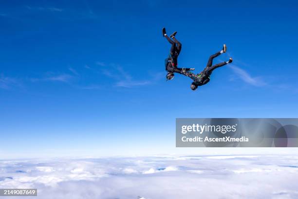 freefall jumpers hold hands upside-down mid-air - free falling stock pictures, royalty-free photos & images