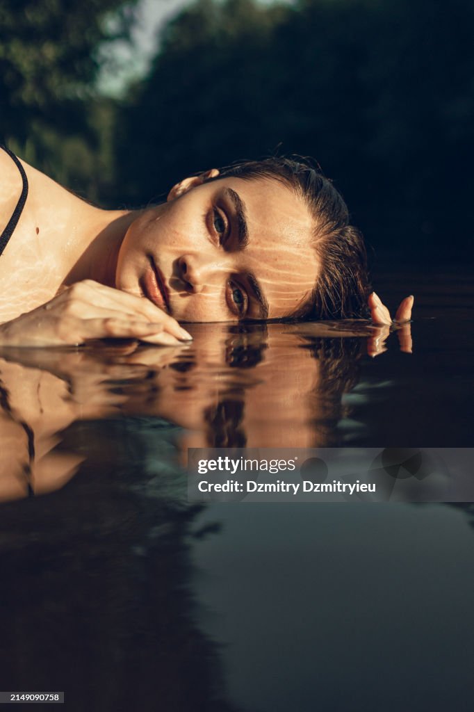 Portrait of beautiful woman with wet hair in water of lake