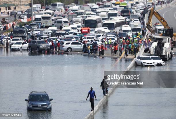 People walk along an flooded highway on April 18, 2024 in Dubai, United Arab Emirates. Atypically heavy rains in the UAE on Monday and Tuesday caused...