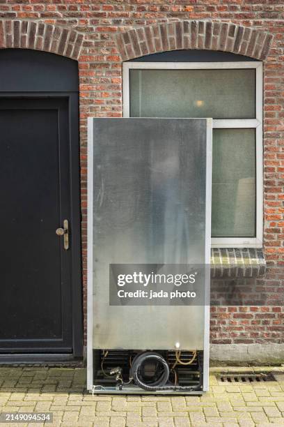 back of a large refrigerator that stands outside on the street - réfrigérateur fermé photos et images de collection