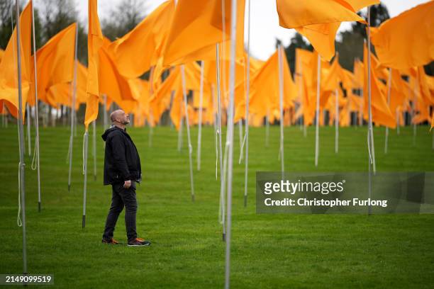 Artist Steve Messam views some of the 500 yellow flags of his installation 'Or' flying in the grounds of Lowther Castle in the Lake District on April...
