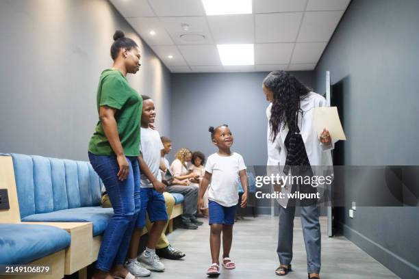 full length female doctor walking with young cute girl in hospital corridor to consultation with family following - doctor stethoscope patient whole body stock pictures, royalty-free photos & images