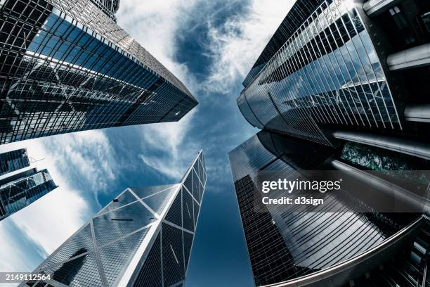low angle view of contemporary corporate skyscrapers with urban architectural design in financial district of hong kong - welvaart stockfoto's en -beelden